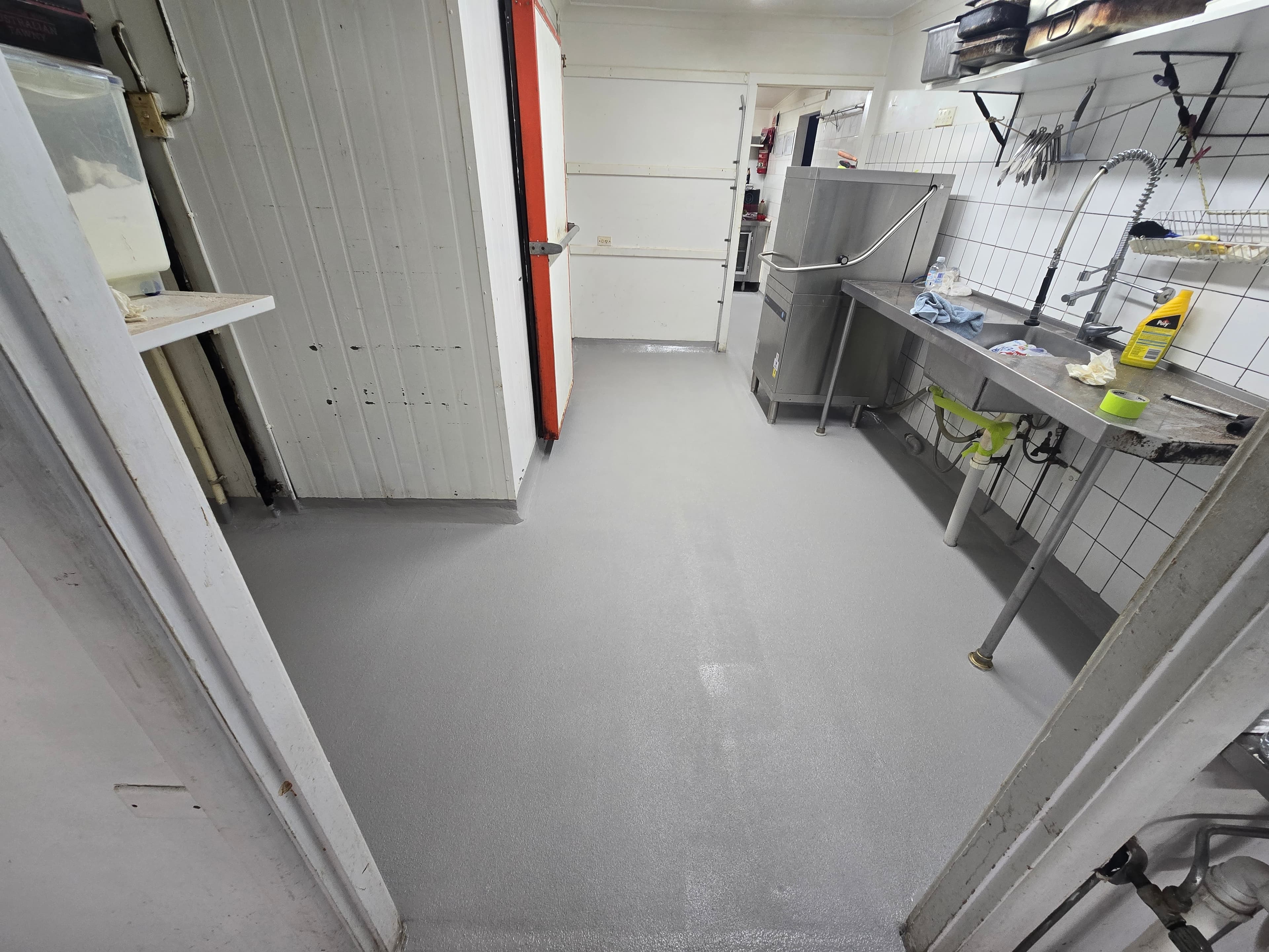 Commercial kitchen floor after epoxy installation - seamless grey anti-slip epoxy coating
