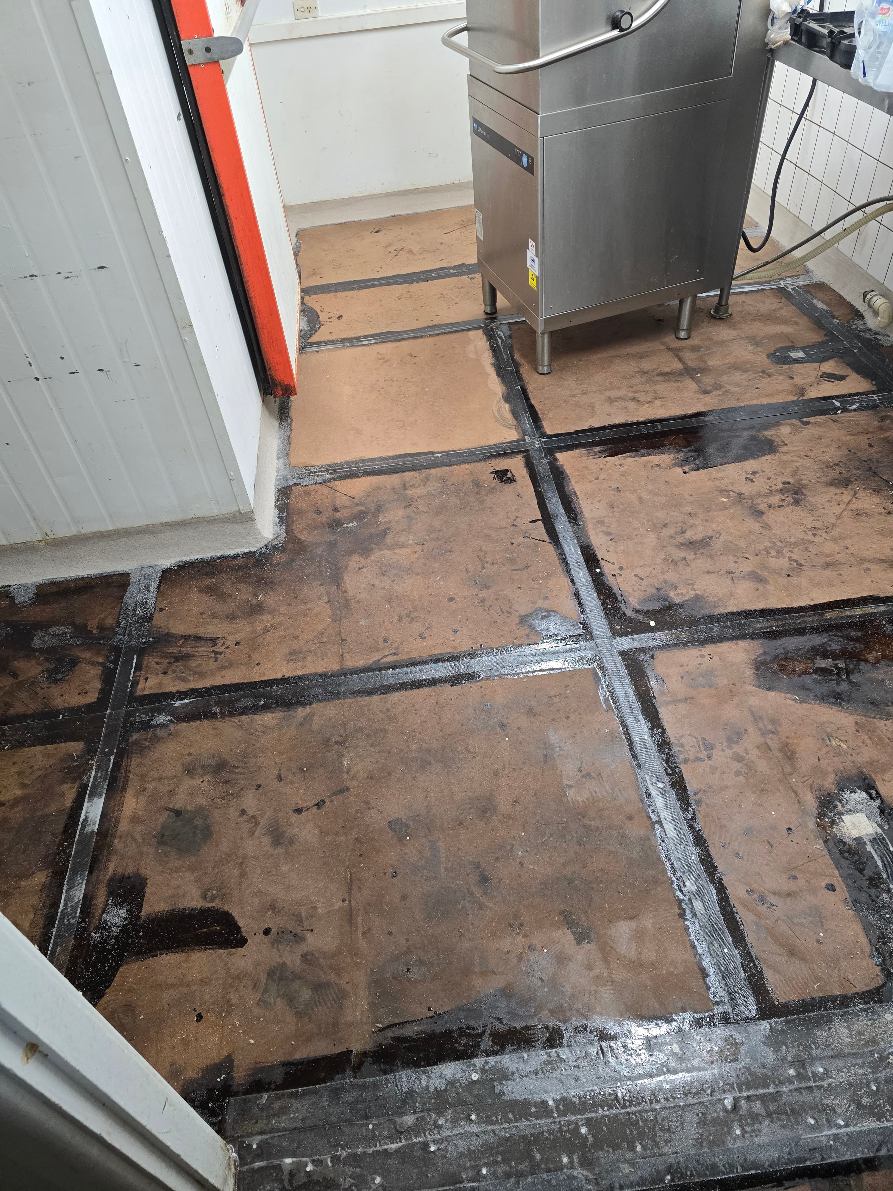 Commercial kitchen floor before epoxy - damaged tiles with grime and cracked grout